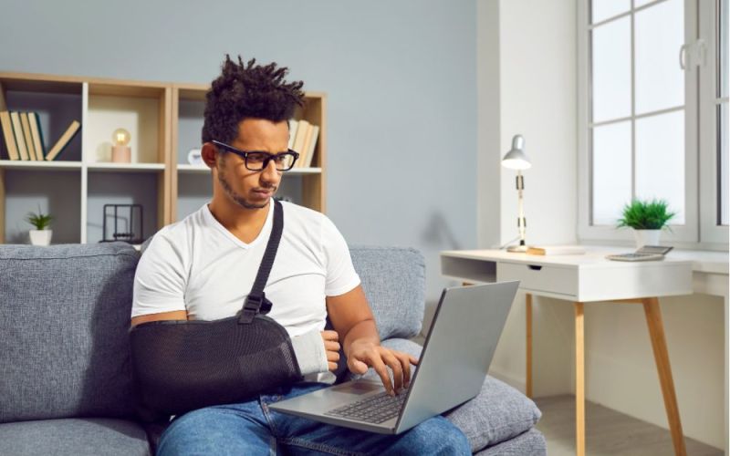 man on his laptop with arm in a sling due to a short term disability