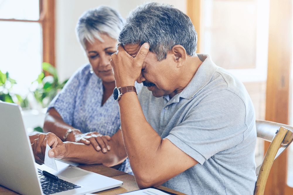 frustrated man at computer with wife consoling him.